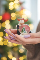 A young girl with a beautiful light purple manicure is holding a snow globe