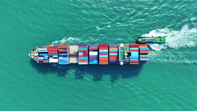 Aerial top view of cargo ship carrying container and running with tug boat for import export goods from cargo yard port to custom ocean concept freight shipping by ship.	
