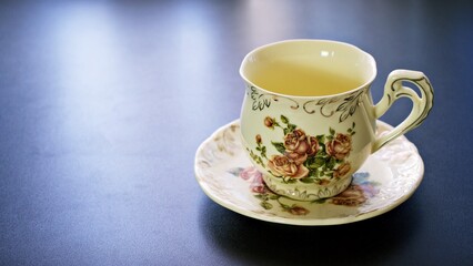 Romantic tea time banner with vintage pink rose porcelain tea cup on a dark gray background ,copy space