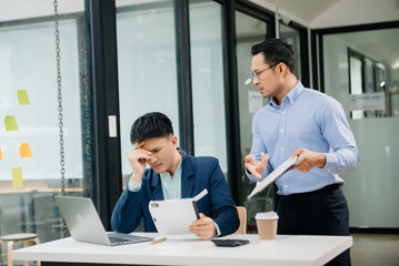 Furious two Asian businesspeople arguing strongly after making a mistake at work in modern office