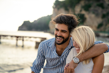 Lovely couple laughing at the beach. Close-up photo of happy attractive couple hugging and smiling next to the sea coast.
