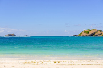 The most beautiful beach in Lombok and the closest to Kuta is Tanjung Aan Beach, A Hidden Gem Waiting for You to Explore on Lombok. beautiful beach surrounded by hills and blue sea