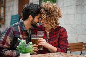 Couple in love drinking beer in the city. Two affectionate people sitting in restaurant, sharing...