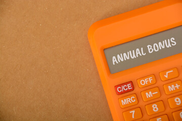 Calculator with text ANNUAL BONUS. An annual bonus is a financial incentive or reward that is typically given to employees by their employers once a year