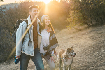 Young man accompanied by his girlfriend walking with dog on nature trail in late Fall. Lovely...