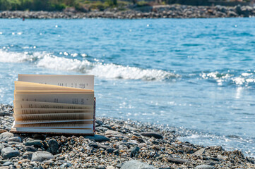 Libro aperto con pagine al vento in riva al mare - obrazy, fototapety, plakaty