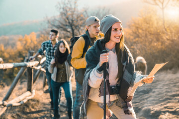 Group of young hikers, walking together. They are carrying hiking poles. Enjoying in the nature and healthy lifestyle.