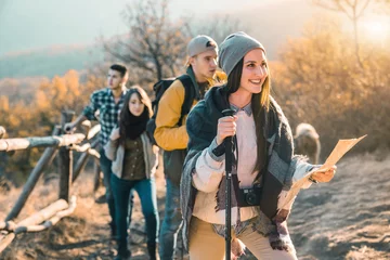 Tuinposter Group of young hikers, walking together. They are carrying hiking poles. Enjoying in the nature and healthy lifestyle. © Dorde