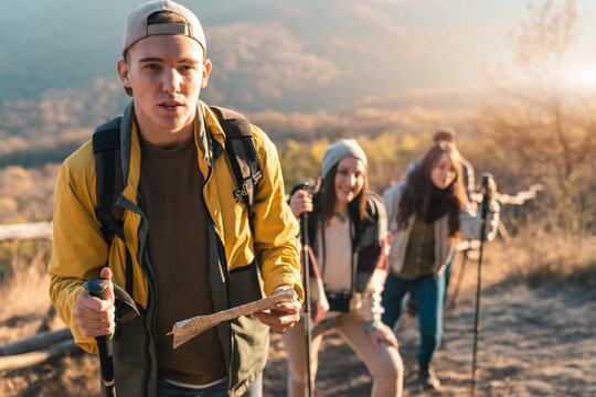 Group of hikers walking in line on a footpath in the mountain, holding a map. Close-up photo of four friends hiking in nature.