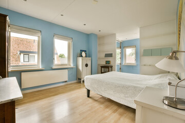a bedroom with blue walls and wood flooring in the middle part of the room there is a white bed