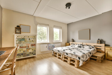 a bedroom with wood flooring and white walls, including a bed made out of wooden pallets on the wall