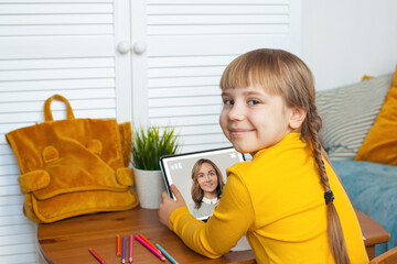 Happy cheerful girl using tablet gadget with teacher on screen. Online courses, classes and education concept.