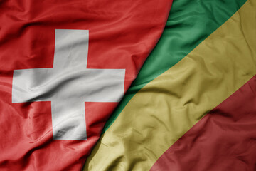 big waving national colorful flag of switzerland and national flag of republic of the congo .