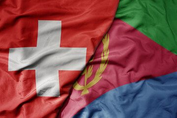 big waving national colorful flag of switzerland and national flag of eritrea .