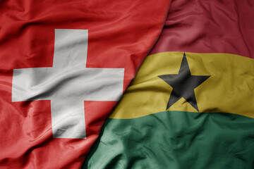 big waving national colorful flag of switzerland and national flag of ghana .