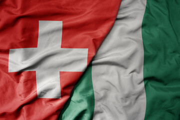 big waving national colorful flag of switzerland and national flag of nigeria .