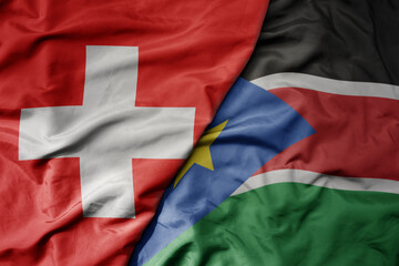 big waving national colorful flag of switzerland and national flag of south sudan