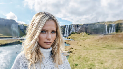 Blonde Iceland girl with beautiful blue eyes looking at an icelandic landscape in the summer