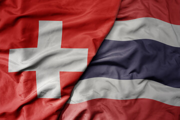 big waving national colorful flag of switzerland and national flag of thailand .