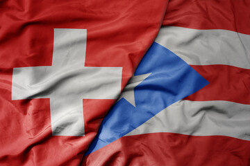 big waving national colorful flag of switzerland and national flag of puerto rico .