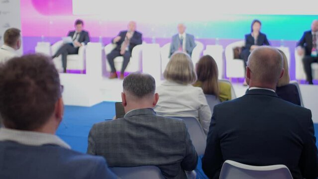 The audience listens to speakers at a business conference. Back view. Slow motion. The concept of education and public speaking.