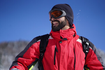 Close-up above the waist photo of smiling young man wearing ski equipment. Happy man wearing ski...