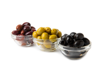 Green, black and red olives isolated on white background. Various types of olives and with fresh olive leaves. Mediterranean food. Vegan.