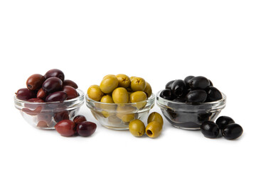 Green, black and red olives isolated on white background. Various types of olives and with fresh olive leaves. Mediterranean food. Vegan.
