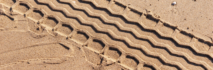 Fototapeta na wymiar Panoramic image. Tire track on the beach. Tire footprint in the sand