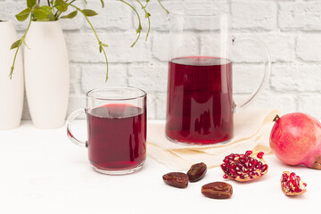 Jug of fruit juice with spices, on wooden table and white background.