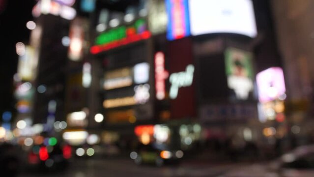 Blurred neon lights and traffic on Shibuya Square in Tokyo, Japan.
