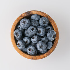 Fresh washed organic blueberries ina olive wood bowl topv view isolated on white