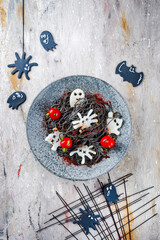 Traditional Halloween octopus spaghetti with Dracula spiders, bats and blood-dripping tomatoes served with spider web as top view in a Nordic design plate  .