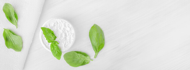 Pure white moisturizer in a white jar.   White towel. Green leaves.