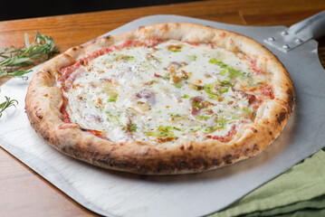 Pizza with ham, tomato sauce, melted cheese and pesto