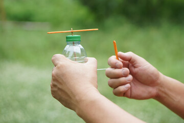Close up hands hold DIY toy made from plastic bottle, rope and ice cream stick. Concept, Recycle...