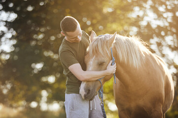 Man is embracing of theraphy horse. Themes hippotherapy, care and friendship between people and animals.. - 645964328