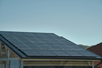 Fototapeta premium House roof with solar panels installed. The integration of solar technology into the roof tiles highlights the innovative approach to energy generation, offering an alternative source of electricity.