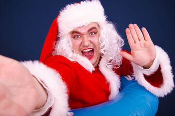 Summer and holidays at sea. A funny drag queen enjoys life in a Santa Claus costume. Blue background.