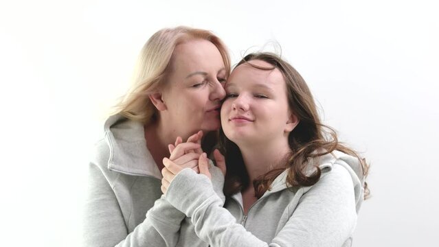 love of daughter and mother hugging kisses tenderness girl kisses her mother's hands mother hugs kisses her daughter on the cheek two women on a light background. a lot of tenderness and joy of love