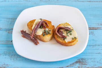 Sandwiches with anchovies, fresh thyme and butter on white plate.
