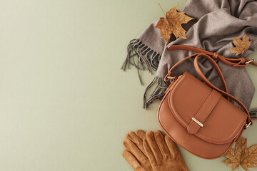 Autumn's refined elegance reflected in every outfit. Top view photo of trendy felt hat, grey scarf, gloves, handbag, autumn leaves on green background with promo zone - obrazy, fototapety, plakaty