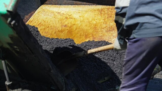 Making new asphalt at road construction. Machine is pouring hot fresh asphalt for road construction. Asphalt laying. Asphalt paver machine on road. Close-up in 4K, UHD