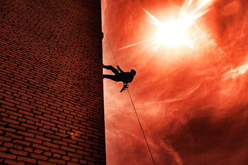 Silhouette of police officer in tactical gear descending from a height, rope exercises with...