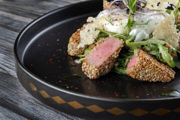 Grilled tuna steak with poached eggs and spinach. Dipped in sesame seeds.
