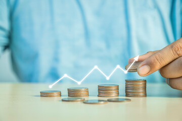 Man putting a coin on a pile of coins. Placing coins in a row from low to high is comparable to saving money to grow more, money-saving concept