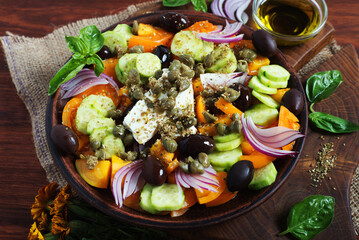 Classic Greek salad with yellow tomatoes, cucumbers, olives, capers and soft cheese. Close-up photo