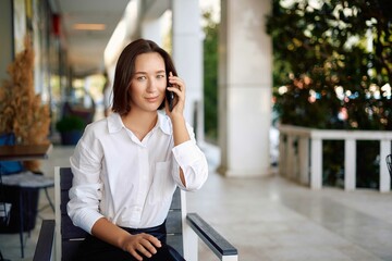 Portrait of a business woman using a phone near the office, concept of a strong and independent woman. Young happy business woman, confident positive female