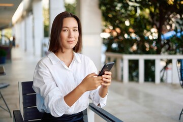 Portrait of a business woman using a phone near the office, concept of a strong and independent woman. Young happy business woman, confident positive female