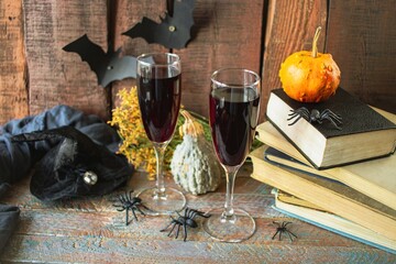 Celebrate Halloween, two glasses of red wine, vintage books, pumpkins and Halloween decorations on a wooden background